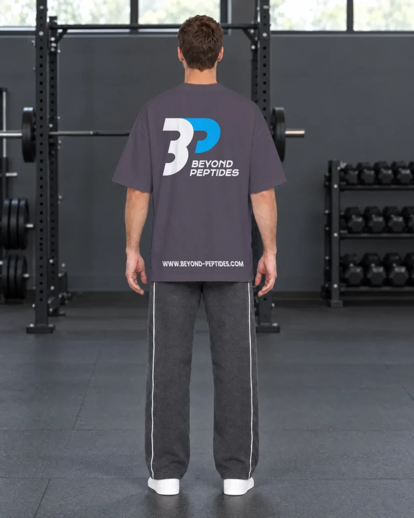 Back view of the Grey Oversized Tee with the large Beyond Peptides print, in a gym