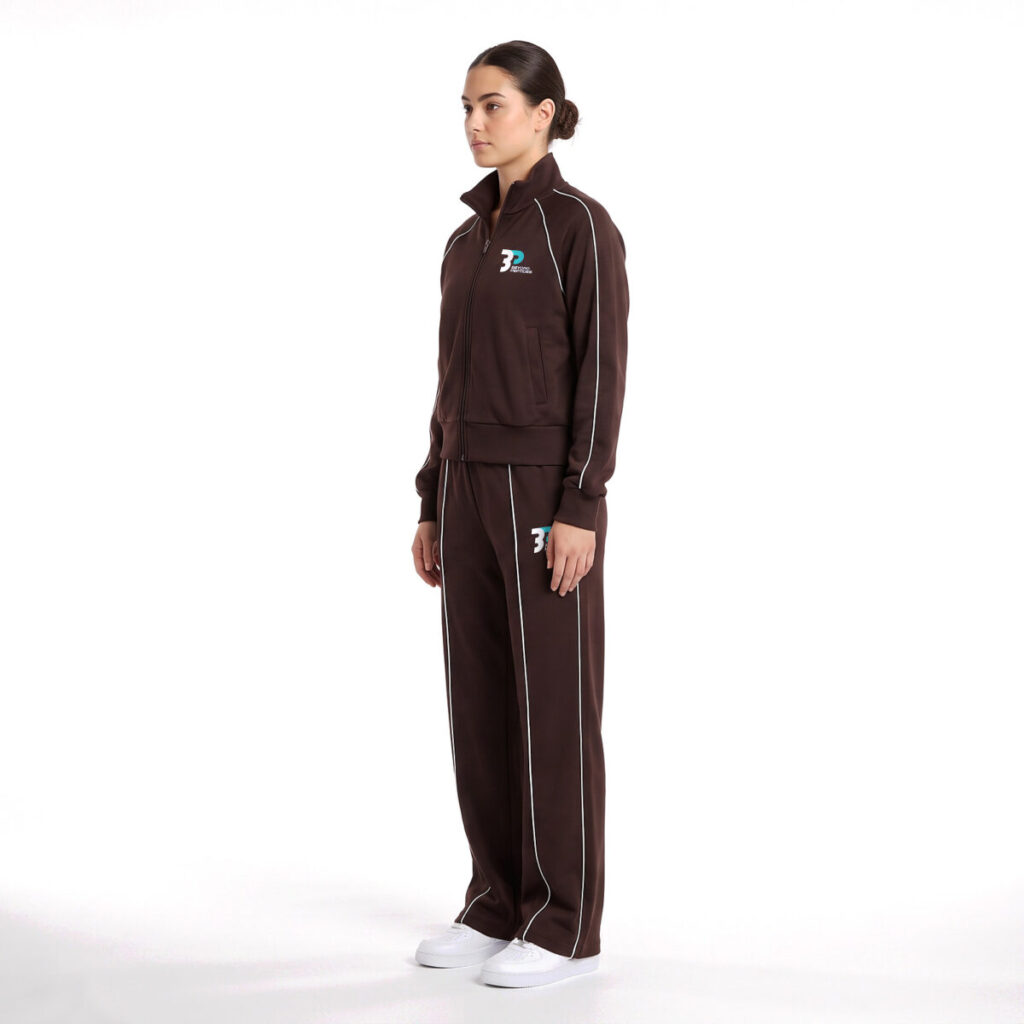 Model wearing the Beyond Peptides Women's Tracksuit Set in dark brown, relaxed fit with wide-leg trousers, side view. AI-generated image, actual product may differ.